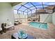 Backyard pool with a screened enclosure, comfortable seating, and a view of the surrounding neighborhood at 2363 Distant Sun Trl, Kissimmee, FL 34747