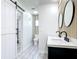 Tastefully designed bathroom with a barn door, modern double vanity, decorative walls, and tiled floors at 2470 Pine Tree Circle Dr, Orange City, FL 32763
