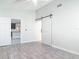 Clean bedroom featuring a sliding barn door, wood-look tile flooring, and soft, neutral paint for a serene space at 2470 Pine Tree Circle Dr, Orange City, FL 32763