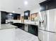 Modern kitchen featuring sleek, dark cabinetry, stainless steel appliances, and stylish backsplash for a luxurious feel at 2470 Pine Tree Circle Dr, Orange City, FL 32763