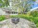 Backyard with mature trees and custom fire pit area and a peek at the home at 2647 Lake Landing Blvd, Eustis, FL 32726