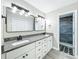Bathroom with dual vanity, granite counter tops, gray wood-look floors, stainless steel hardware, and access to a walk-in shower at 2647 Lake Landing Blvd, Eustis, FL 32726