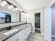 Well lit bathroom with dual vanity, granite counter tops, gray wood-look floors, and stainless steel hardware at 2647 Lake Landing Blvd, Eustis, FL 32726