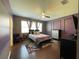 Stylish main bedroom features hardwood floors, ceiling fan, a calming purple accent wall, and bright windows at 2865 Running Brook Cir, Kissimmee, FL 34744