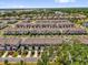 Wide aerial view of a townhome community boasts a dense suburban landscape with mature trees and street parking at 3039 Springwell Loop, Orlando, FL 32808