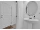 A crisp, minimalist bathroom featuring a pedestal sink and round mirror, creating a clean and modern space at 3039 Springwell Loop, Orlando, FL 32808