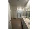 Bright bathroom with double vanity, framed mirror, and tile flooring leading to a glass shower at 34071 Sky Blossom Cir, Leesburg, FL 34788