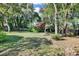 Lush backyard featuring mature trees, flowering shrubs, green grass, and a wooden fence at 3517 Merivale Dr, Casselberry, FL 32707