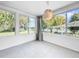 Bright sunroom features white tile floor and large windows showcasing an outdoor view with mature trees and a lake at 407 Sheryl Dr, Deltona, FL 32738