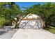 Home's 2-car garage with a concrete driveway and mature landscaping with flowering trees at 4336 Cloverleaf Pl, Casselberry, FL 32707