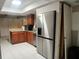 Open kitchen with granite counters, wood cabinets, stainless fridge, and tile floors at 4838 Pebble Beach Dr # A, Orlando, FL 32811
