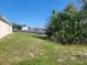 A view of the home's backyard shows the lawn area, mature trees, and white fence at 506 Peace Way, Kissimmee, FL 34759