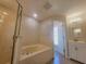 A pristine main bathroom has a glass shower, a large tub, and vanity with good lighting at 506 Peace Way, Kissimmee, FL 34759