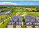Aerial shot of modern townhomes with a view of the adjacent golf course, vibrant greenery, and partly cloudy sky at 507 Ocean Course Ave # 507, Davenport, FL 33896