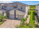 Modern townhome with two-car garage, stone accents, brick driveway, and landscaping; golf course in the background at 507 Ocean Course Ave # 507, Davenport, FL 33896