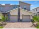 A modern townhome boasts a two-car garage with brick driveway and stone accents, complemented by lush palm trees at 507 Ocean Course Ave # 507, Davenport, FL 33896