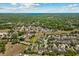 A scenic aerial view showcases the home's surroundings with lush trees, a lake, and a vibrant neighborhood at 528 Seven Oaks Blvd, Winter Springs, FL 32708