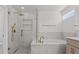 Bright bathroom features a tub and shower with elegant gold fixtures and neutral tiling at 528 Seven Oaks Blvd, Winter Springs, FL 32708