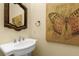 Bathroom featuring a pedestal sink, decorative mirror, and butterfly wall art at 724 Wildmere Village Cv, Longwood, FL 32750