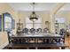 Well-lit dining area featuring a long table, statement chandelier, and hardwood floors at 724 Wildmere Village Cv, Longwood, FL 32750