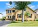 Beautiful two-story house featuring palm trees, lush landscaping, and charming shutters at 724 Wildmere Village Cv, Longwood, FL 32750