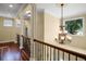 Bright hallway features hardwood floors, decorative chandelier, and architectural pillars at 724 Wildmere Village Cv, Longwood, FL 32750
