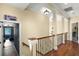 Beautiful upstairs hallway boasts gleaming hardwood floors, decorative columns, and view to movie room at 724 Wildmere Village Cv, Longwood, FL 32750