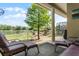Covered patio with seating overlooks a lush backyard, lake, playground and screened pool at 724 Wildmere Village Cv, Longwood, FL 32750