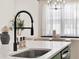 Kitchen sink with black faucet and spring neck sits atop a white quartz countertop in the modern kitchen at 765 Terrapin Dr, Debary, FL 32713