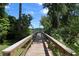 Picturesque wooden walkway leading to a serene dock with lush greenery under a bright blue sky at 821 N Lake Claire Cir, Oviedo, FL 32765