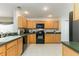 Well-lit kitchen with tile floors, wood cabinets, and black appliances at 821 N Lake Claire Cir, Oviedo, FL 32765