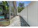 Side yard with a gravel walkway, white fence, and access to a screened-in patio at 821 N Lake Claire Cir, Oviedo, FL 32765
