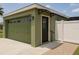 Green single car garage and entry door with awning plus a white fence at 8325 Sun Vista Way, Orlando, FL 32822
