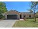 Charming single-story home with a well-manicured lawn, stone accents, and a two-car garage at 10030 Cheshunt Dr, Orlando, FL 32817