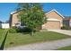 Landscaped front yard features a young tree, green lawn, and home with a two-car garage at 1052 Cascade Dr, Davenport, FL 33837