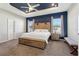 Spacious main bedroom with a tray ceiling, blue accent wall and a large wooden bed frame at 1052 Cascade Dr, Davenport, FL 33837