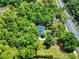 Aerial view of a property surrounded by lush trees, complemented by a view of the adjacent road at 1155 Taylor E Rd, Deland, FL 32724