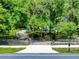 Gated driveway leading to a beautiful white home surrounded by a lush landscape of trees at 1155 Taylor E Rd, Deland, FL 32724