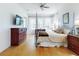 Bright main bedroom featuring hardwood floors, ceiling fan, and large windows with sheer white curtains at 1155 Taylor E Rd, Deland, FL 32724