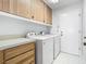 Well-lit laundry room featuring cabinetry above front loading washer and dryer at 1157 Valley Creek Run, Winter Park, FL 32792