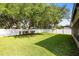 Well-manicured backyard featuring lush green grass, mature trees, and a pristine white fence for privacy at 1174 Snug Harbor Dr, Casselberry, FL 32707