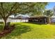 Large, well-maintained backyard featuring a lush lawn, mature trees, and a screened lanai at 1174 Snug Harbor Dr, Casselberry, FL 32707