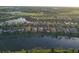 This aerial view presents a neighborhood with residences along a pond, complemented by green spaces and mature trees at 11962 Autumn Fern Ln, Orlando, FL 32827