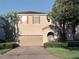 Two-story home featuring a tile roof, two-car garage, brick driveway, arched entryway, and verdant landscaping at 11962 Autumn Fern Ln, Orlando, FL 32827