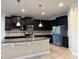 Modern kitchen featuring dark cabinetry, granite countertops, pendant lights, and stainless steel appliances at 11962 Autumn Fern Ln, Orlando, FL 32827