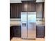 Close up of stainless steel fridge, dark cabinets, and granite countertops at 11962 Autumn Fern Ln, Orlando, FL 32827