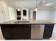 Kitchen island with stainless steel dishwasher, dark cabinets and granite countertop at 11962 Autumn Fern Ln, Orlando, FL 32827