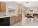 Bright eat-in kitchen with light wood cabinets, stainless steel sink, and tile flooring adjacent to dining area at 126 Knights Hollow Dr, Apopka, FL 32712