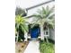 Charming home entry with vibrant blue door, tropical landscaping, and seating area at 1309 Harms Way, Port Orange, FL 32129
