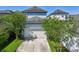 Exterior view of a two-story home with a white garage door, complemented by lush green landscaping and trees at 13890 Sato Ave, Orlando, FL 32827